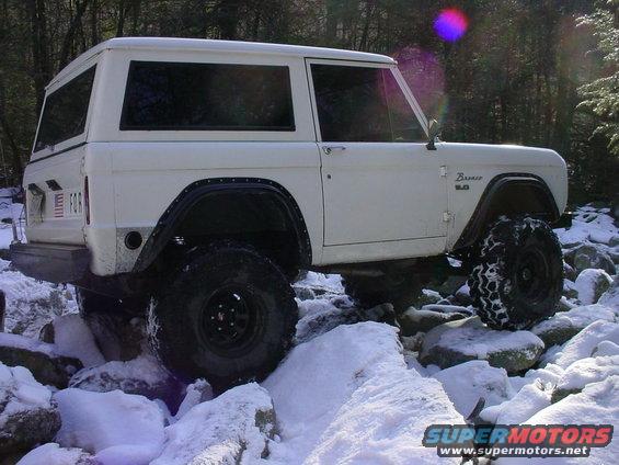 1969 Ford Bronco with large tires navigating rocky, snowy terrain