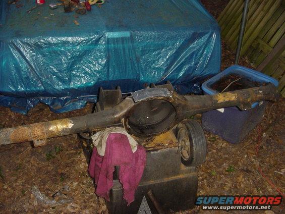 Ford rear axle housing with differential cover removed, resting on a black bin