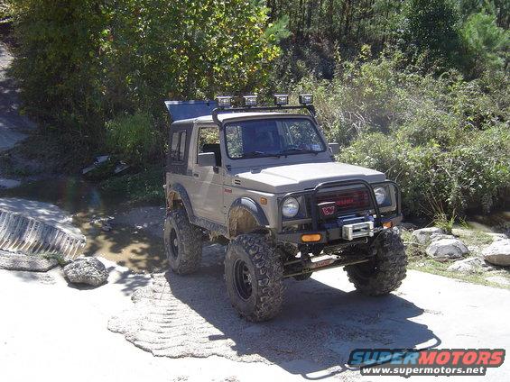 Tan Suzuki Samurai with off-road tires, winch, and roof rack