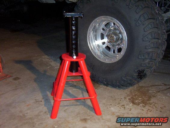 Red jack stand next to a massive off-road tire on a vehicle