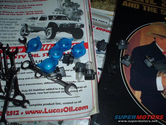 Wrenches, blue bulb covers, and light bulbs on top of automotive literature