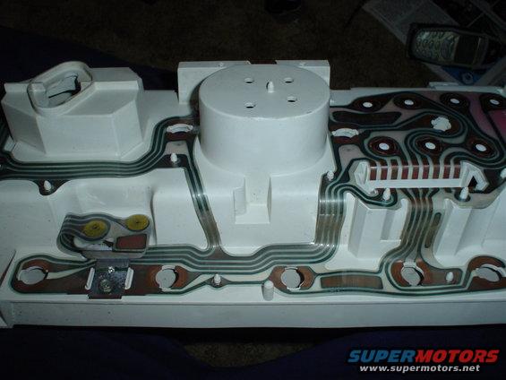 Back of a white dashboard instrument cluster with green and brown wiring traces