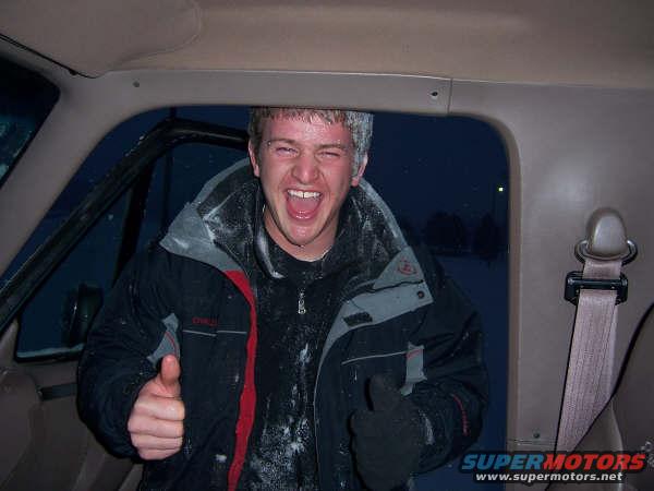 Man inside vehicle covered in snow, giving thumbs up