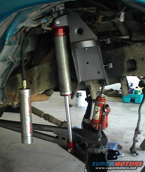 Close-up of a vehicle's front suspension with a new shock absorber and a jack holding it up