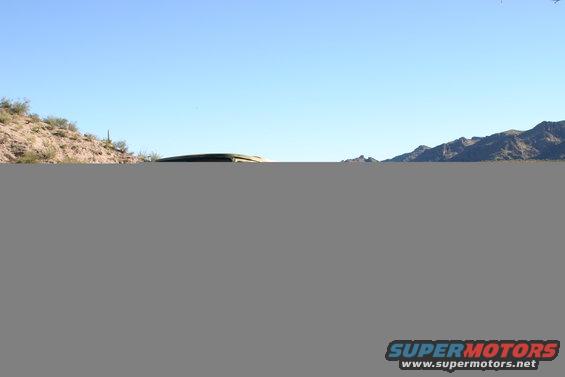1978 Ford Bronco parked on a dirt road with desert mountains in the background