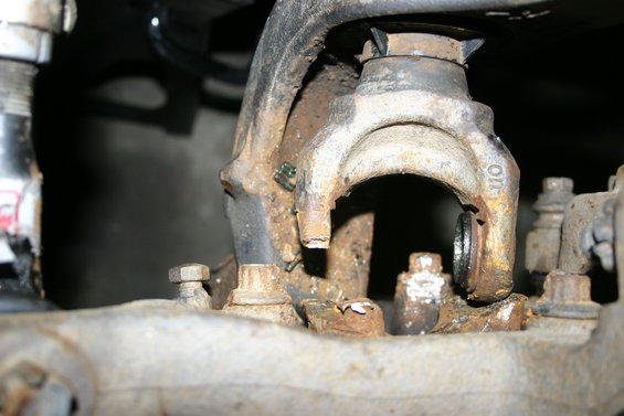Close-up of heavily rusted suspension parts, including bolts and a bracket