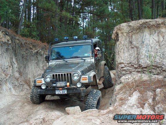 Gray Jeep Wrangler TJ navigating a dirt trail with a winch on the front