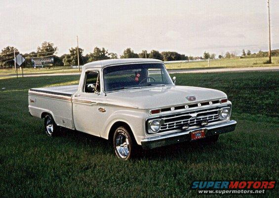 White 1965 Ford F-100 pickup truck parked on grass, front 3/4 view