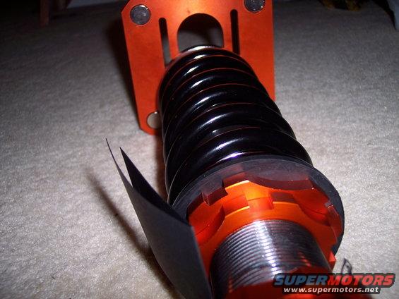 Orange and black coilover suspension part with adjustable spring perch and threaded body