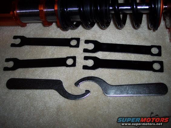 Adjustable coilover suspension parts with wrenches. Includes two coilover units and six adjustment wrenches