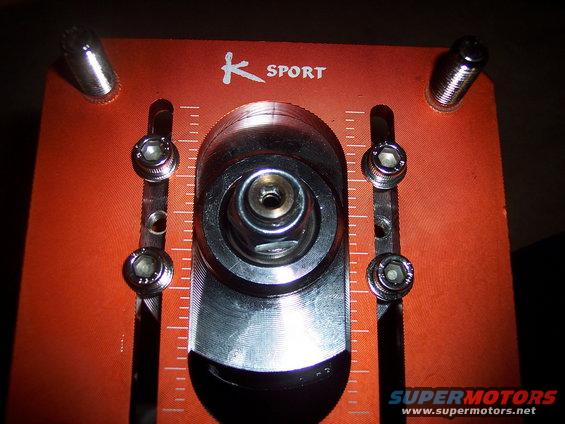 Close-up of an orange K-Sport adjustable strut mount with hex bolts and measurement markings