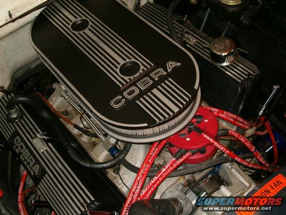 Engine bay with black Cobra valve covers and red spark plug wires. A "SUPERMOTORS.NET" watermark is visible