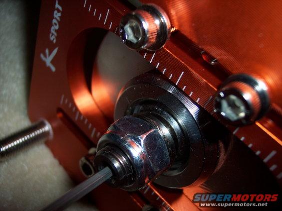 Close-up of an orange K Sport adjustable suspension part with hex key and bolts