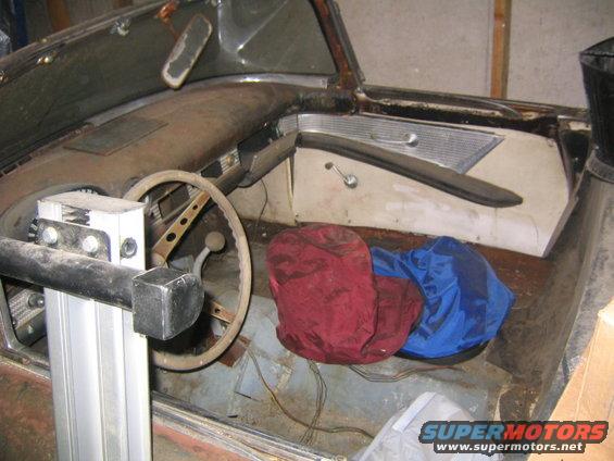 1956 Ford Thunderbird interior showing dashboard, steering wheel, and seats covered with red and blue bags