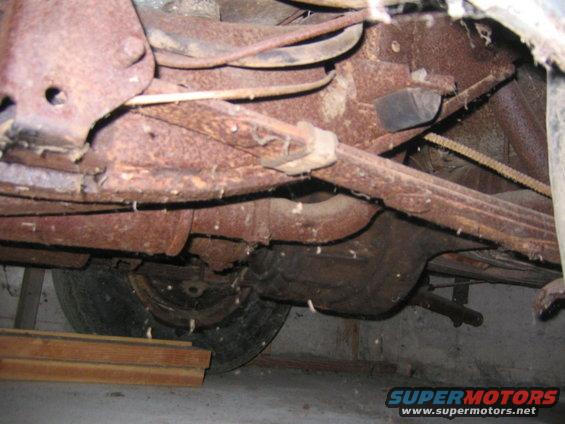 Underbody view of rusty car with leaf springs and tire