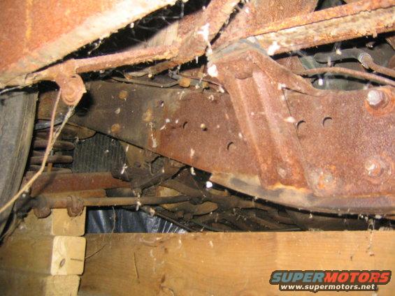 Rusty frame rails, suspension components, and a tire visible under a vehicle