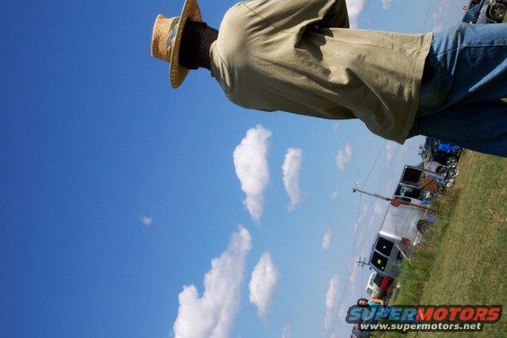 Person in straw hat, vehicles in background, Supermotors logo