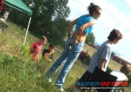 Red tractor in grassy field with people