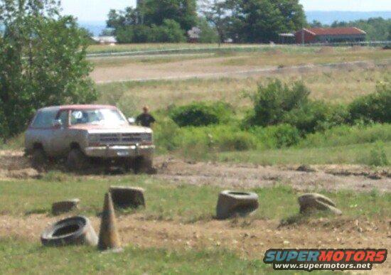 Dodge Ramcharger driving through mud with a person standing nearby