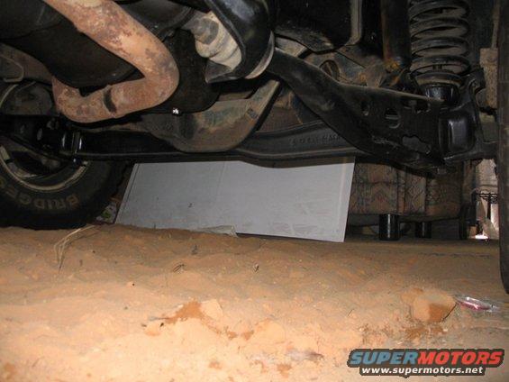 Undercarriage view of a vehicle, showing suspension and exhaust components. Text on tire reads BRIDGE