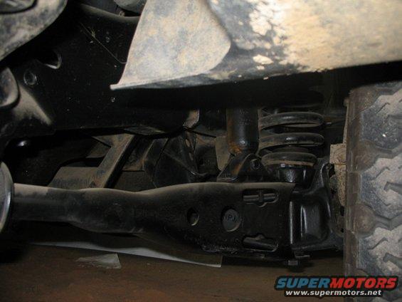 Close-up of a vehicle's front suspension components, including a control arm and coil spring