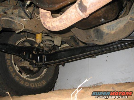 Underside view of a vehicle's suspension and exhaust system, showing a Bridgestone tire