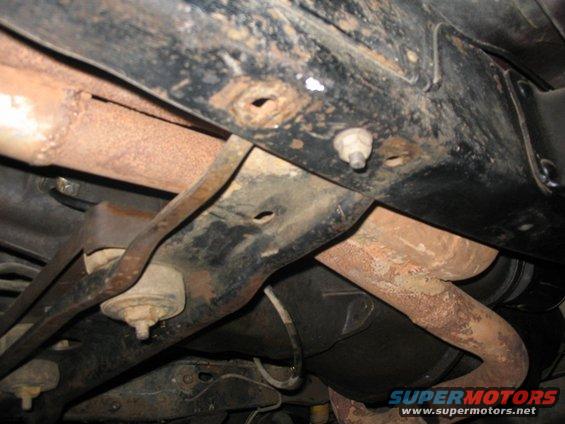 Underside view of rusty exhaust pipes and frame components, possibly from an older truck or SUV
