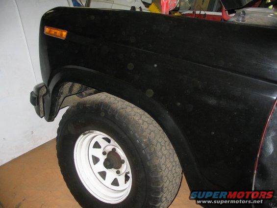 Black SUV fender and white-rimmed wheel with visible water spots and dirt