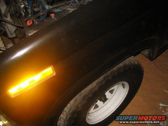 Black vehicle fender with amber turn signal and white rim wheel
