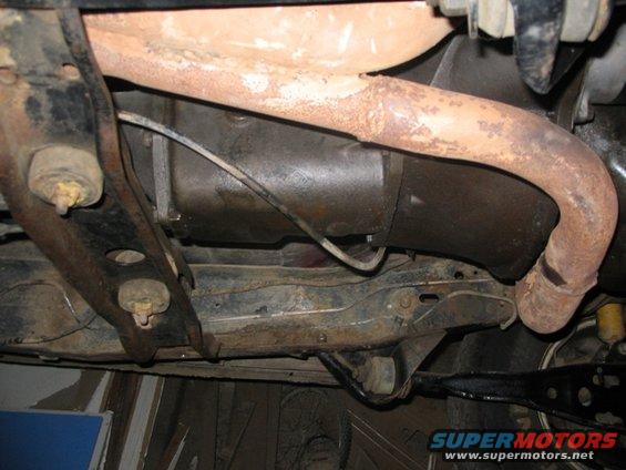 Undercarriage view of rusty exhaust pipe and frame components