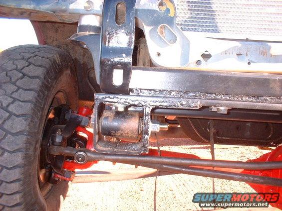 Close-up of a truck's front suspension and radiator assembly. Shows red shocks and suspension components