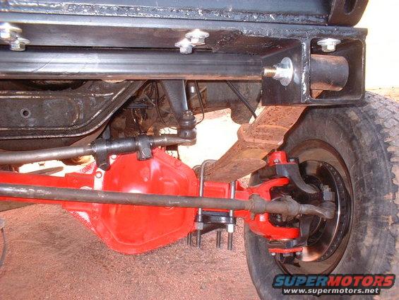 Close-up of red-painted differential, leaf spring, and steering linkage on a truck