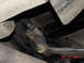 1990 Ford Bronco - A close-up view of a rusty metal bracket attached to the undercarriage of a vehicle.