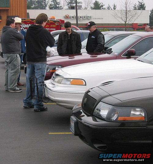 Black 1998 Ford Crown Victoria front grille and headlights, parked next to a white Crown Victoria