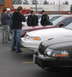 1999 Ford Crown Victoria - Several Ford Crown Victorias are parked in a lot, with people standing around them.