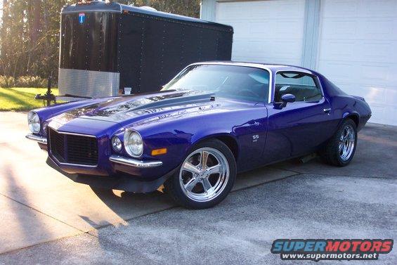 Purple 1970 Chevrolet Camaro SS with chrome wheels parked in front of a garage and trailer