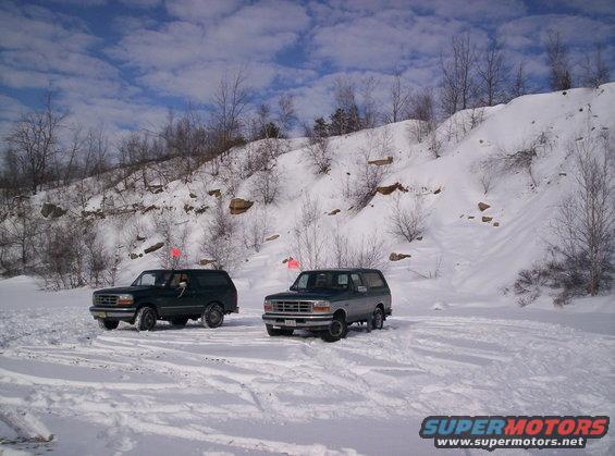 Two 1996 Ford Broncos parked in a snowy landscape with a rocky hill in the background