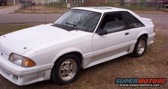 White coupe with aftermarket wheels and a spoiler