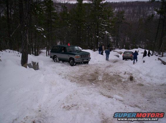 1996 Ford Bronco and another SUV on a snowy trail with trees in the background