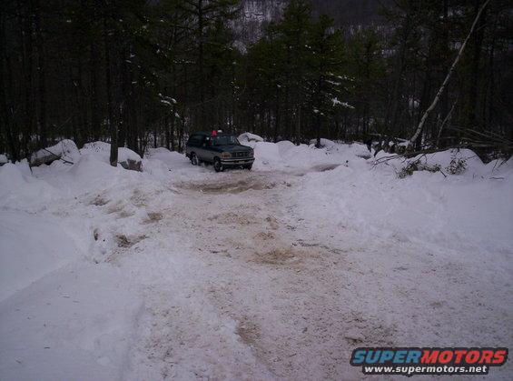 1996 Ford Bronco driving on a snow-covered dirt road