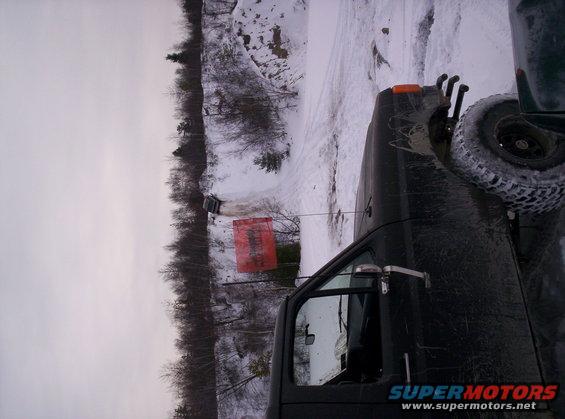 Dark SUV with spare tire on rear, seen from the side in a snowy landscape