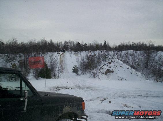 Dark Ford Bronco in snow, front quarter view. Red flag with text visible