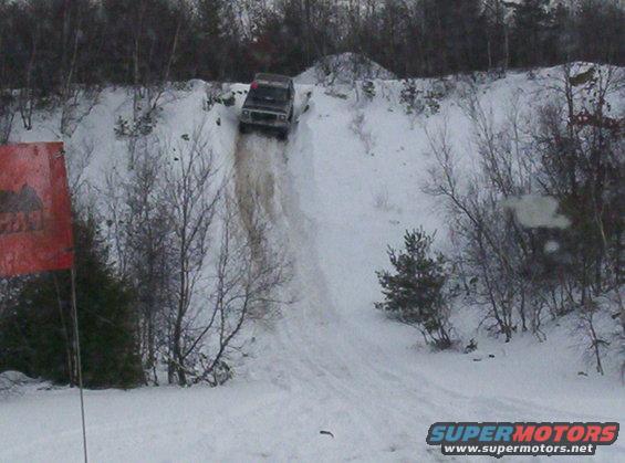 Dark 1996 Ford Bronco driving down a steep snowy hill