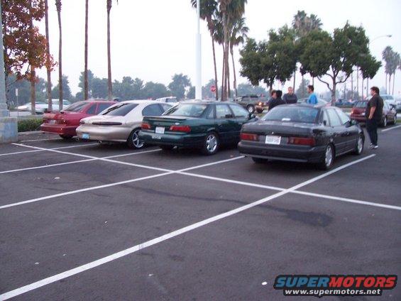 Four sedans parked in a lot, three in a row and one to the right