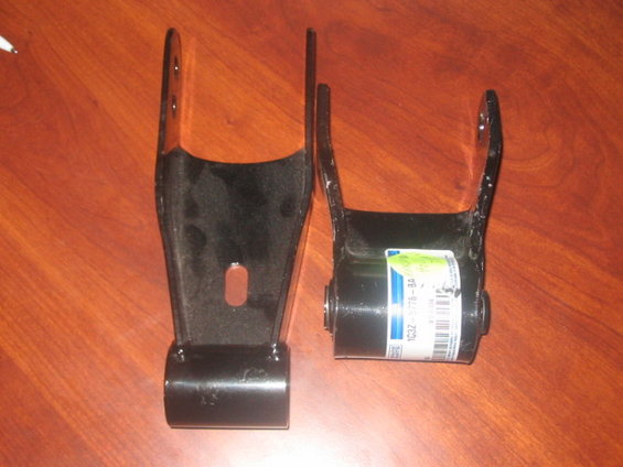 Two black leaf spring shackles, one with a label showing part number 1C3Z-5776-BA