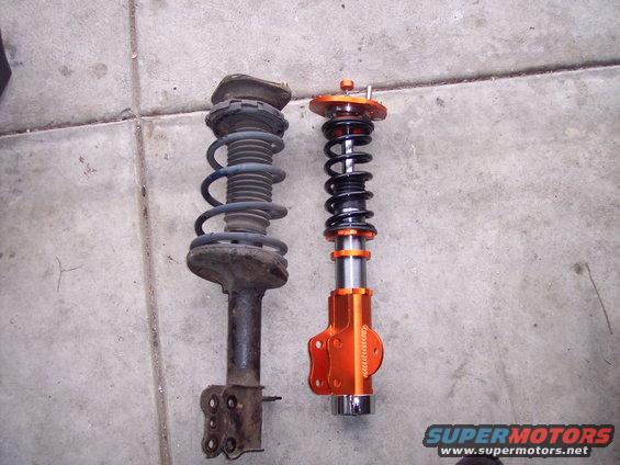 Two suspension struts, one old and rusty, the other new and orange with adjustable coilovers