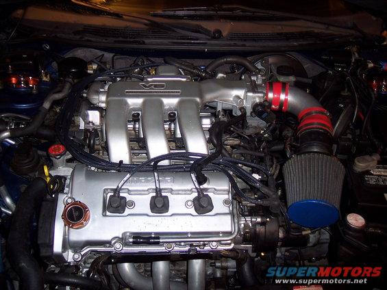 Engine bay showing V6 intake manifold and aftermarket air filter. 'MAZDA' is visible on the valve cover