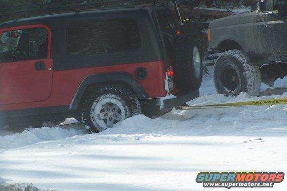 Red Jeep Wrangler stuck in snow with another vehicle behind it