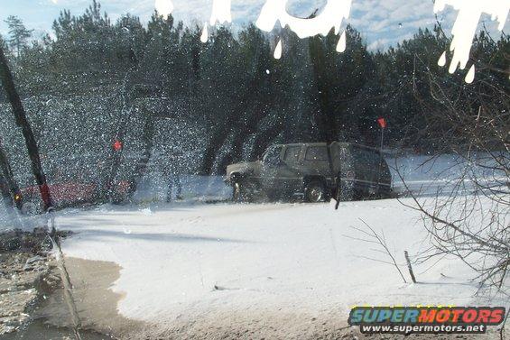 Off-road vehicle driving through snow with another vehicle partially visible behind it