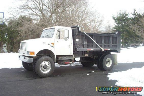White dump truck with a black bed, parked outside